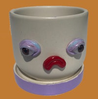 a ceramic cup with a sad face on it