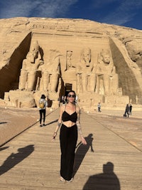 a woman standing in front of an egyptian sphinx