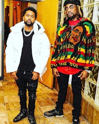 two men standing next to each other in a hallway
