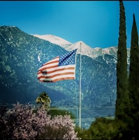 an american flag flies in front of mountains