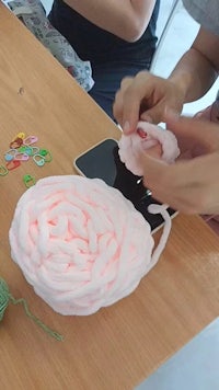 a person is making a crochet flower on a table