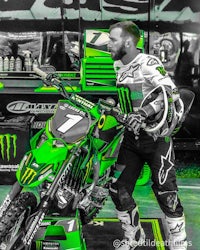a man standing next to a green monster energy dirt bike