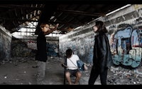 a group of people standing in an abandoned building with graffiti on the walls