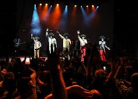 a group of people on stage with their hands raised