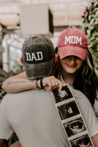 two people hugging and wearing hats that say dad and mom