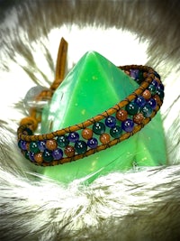 a bracelet with multi colored beads and a green crystal