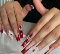a woman with red and white nails with flowers on them