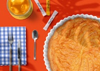 a pie is sitting on a table next to a glass of orange juice