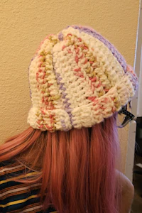 a woman with pink hair wearing a knitted hat