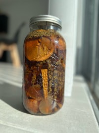 a mason jar filled with dried mushrooms on a window sill