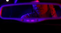 a woman is seen in the rear view mirror of a car at night