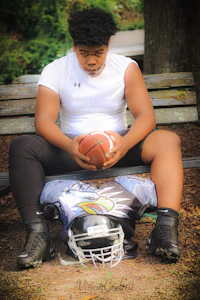a young man sitting on a bench holding a football