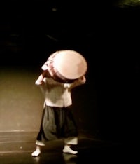a man holding a large drum in the dark