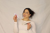 a woman holding a toothbrush and lipstick
