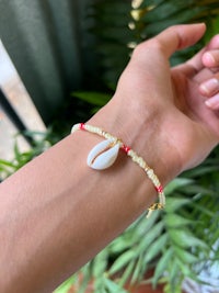 a woman wearing a bracelet with a shell on it