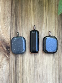 three black stone pendants on a wooden table