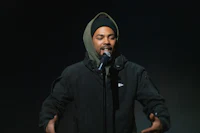 a man in a black jacket is holding a microphone