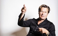 a man in a black shirt pointing his finger