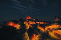a minecraft village lit up at night