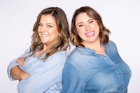 two women posing for a photo in front of a white background