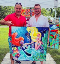 two men posing in front of a painting