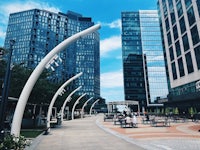 a city with tall buildings and a sidewalk with benches