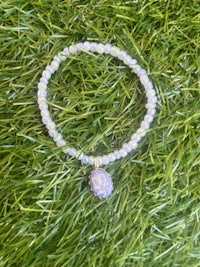 a bracelet with a purple stone on top of grass