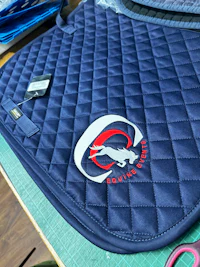 a blue quilted saddle pad with a logo on it