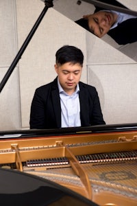 a man in a suit playing a grand piano
