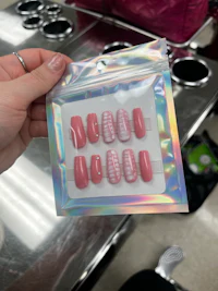 a person holding a package of pink nail polish