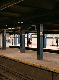 an empty subway station with people standing on the platform