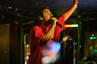 a man in a red shirt singing into a microphone