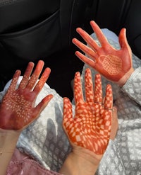 two people sitting in a car with their hands painted with henna