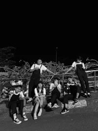 a black and white photo of a group of people sitting on a railing