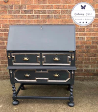 a black desk with brass handles and drawers