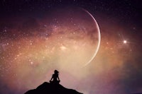 a woman sitting on top of a mountain looking at the stars
