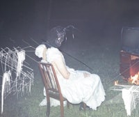 a woman sits on a chair in front of a television