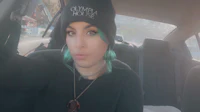 a woman with green hair sitting in the back seat of a car