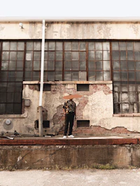 a man is standing on a ledge next to a building