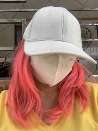 a woman with pink hair wearing a hat