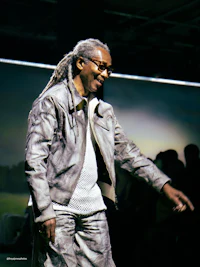 a man with dreadlocks wearing a jacket and pants
