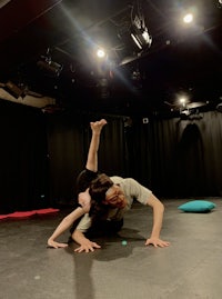 two people doing acrobatics in a black room