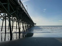 a pier in the ocean with the sun shining on it