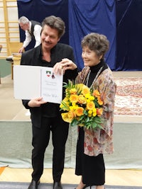 a man and woman standing next to each other holding a certificate