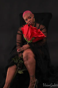 a woman sitting on a chair holding a red rose