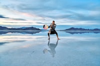 a man holding a surfboard in the middle of the salt flats