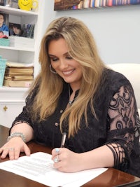 a woman sitting at a desk signing a document