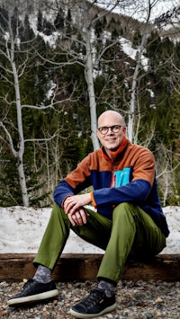 a man sitting on a bench in front of a snowy mountain