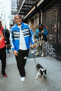 two men walking a dog on a sidewalk