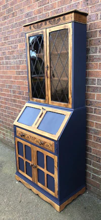 a blue and gold bookcase with glass doors